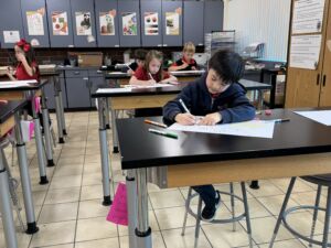 a young boy focusing on his drawing at the art tables.