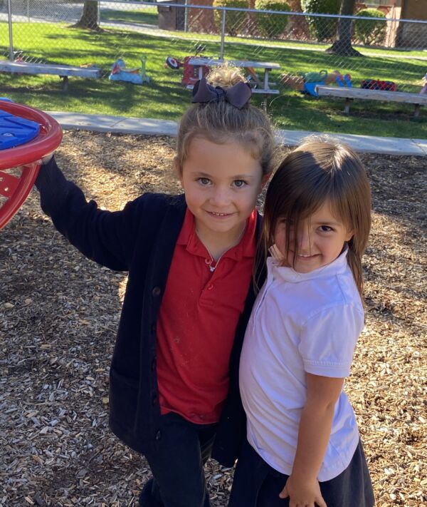 two girls in Pre-K with their arms around each other smiling