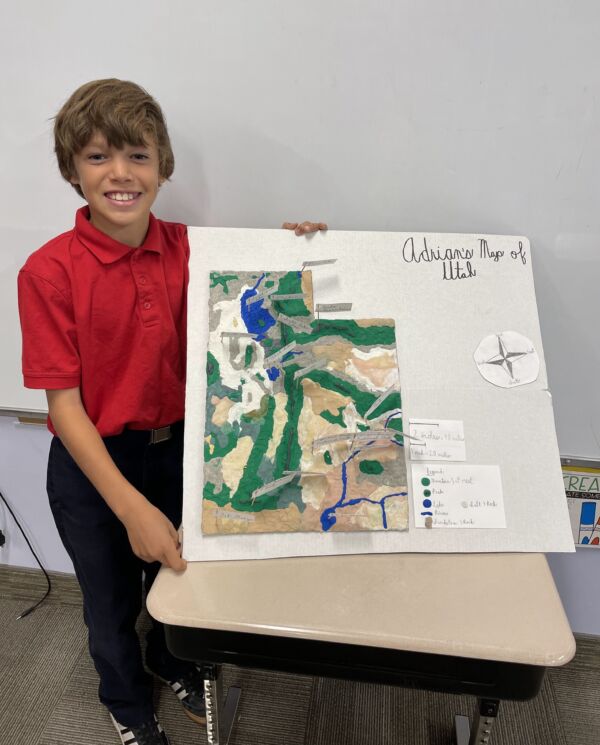 student smiling showing off his state report on the state of Utah in third grade